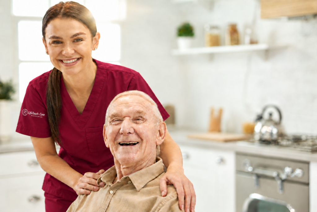 LifeTouch Care carer in burgundy scrubs with an embroidered sleeve logo