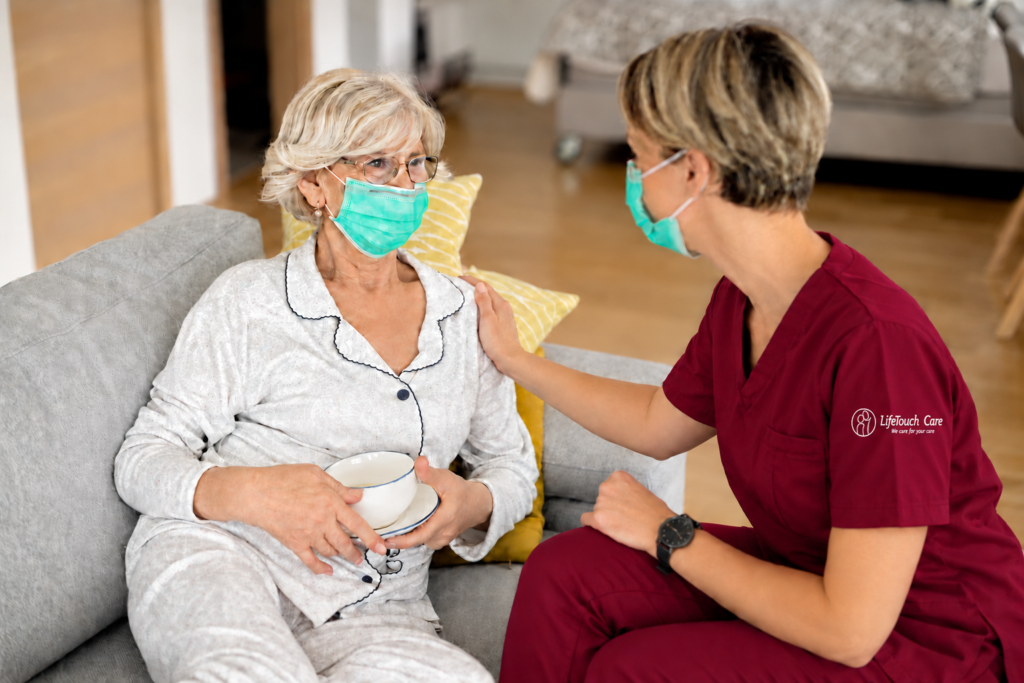 LifeTouch Care carer in burgundy scrubs with an embroidered sleeve logo