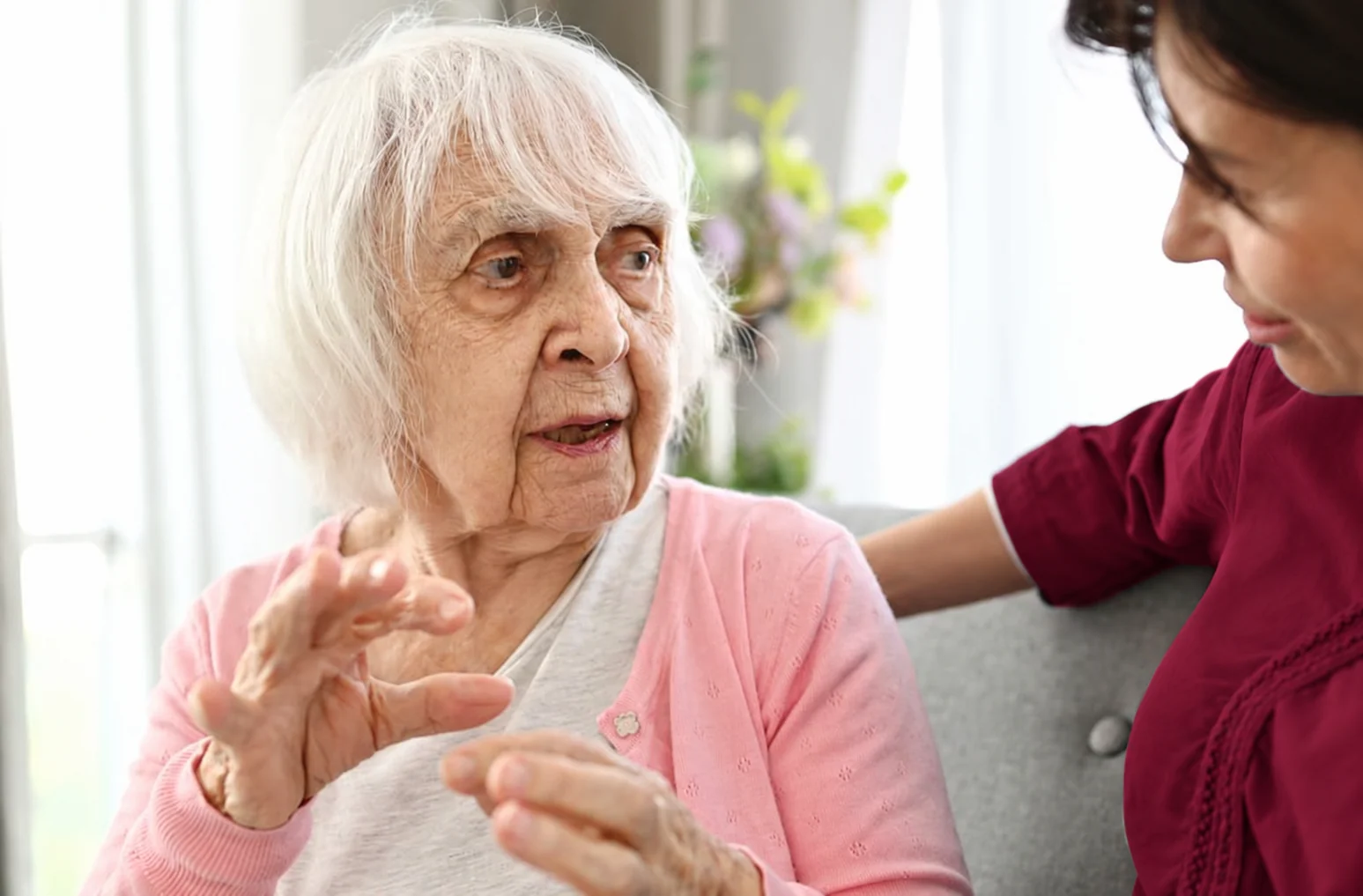 Care professional in a matching burgundy uniform supporting a patient.