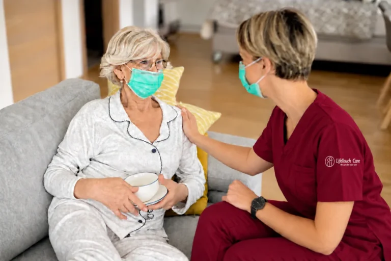 LifeTouch Care carer in burgundy scrubs with an embroidered sleeve logo