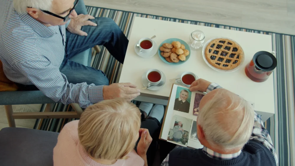 Older friends enjoying a photo album and conversation around a table